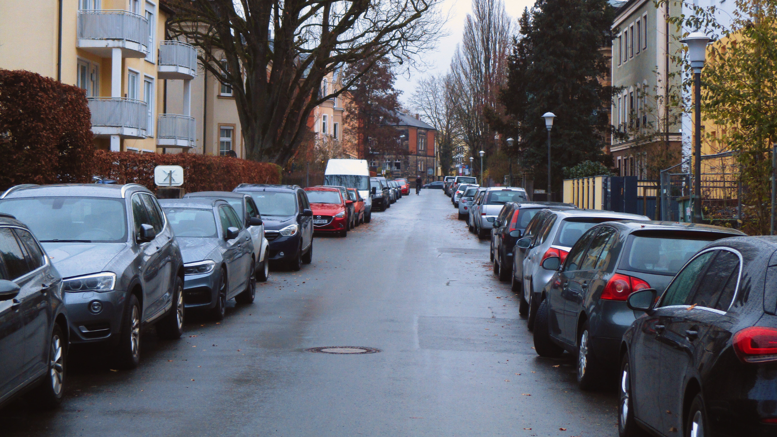 Das Foto zeigt eine Straße mit Autos, die am Straßenrand parken.